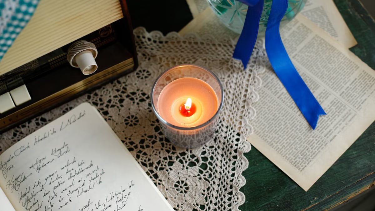 Cozy vintage scene with candlelight, radio, and handwritten manuscript on lace.